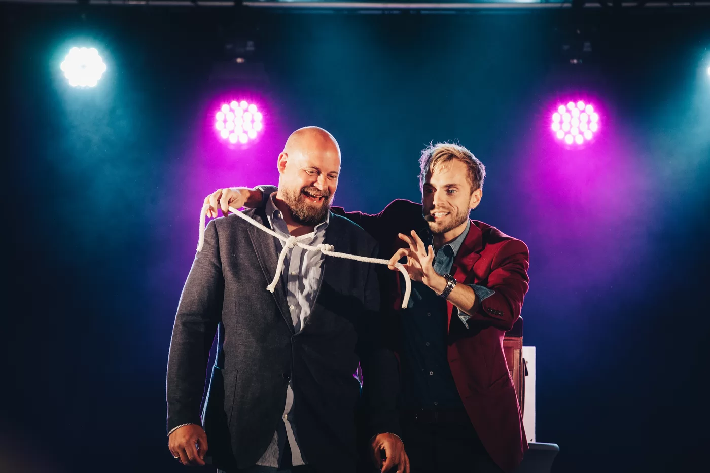 Hans Grane in an orange jacket performing a rope routine with a delighted guest