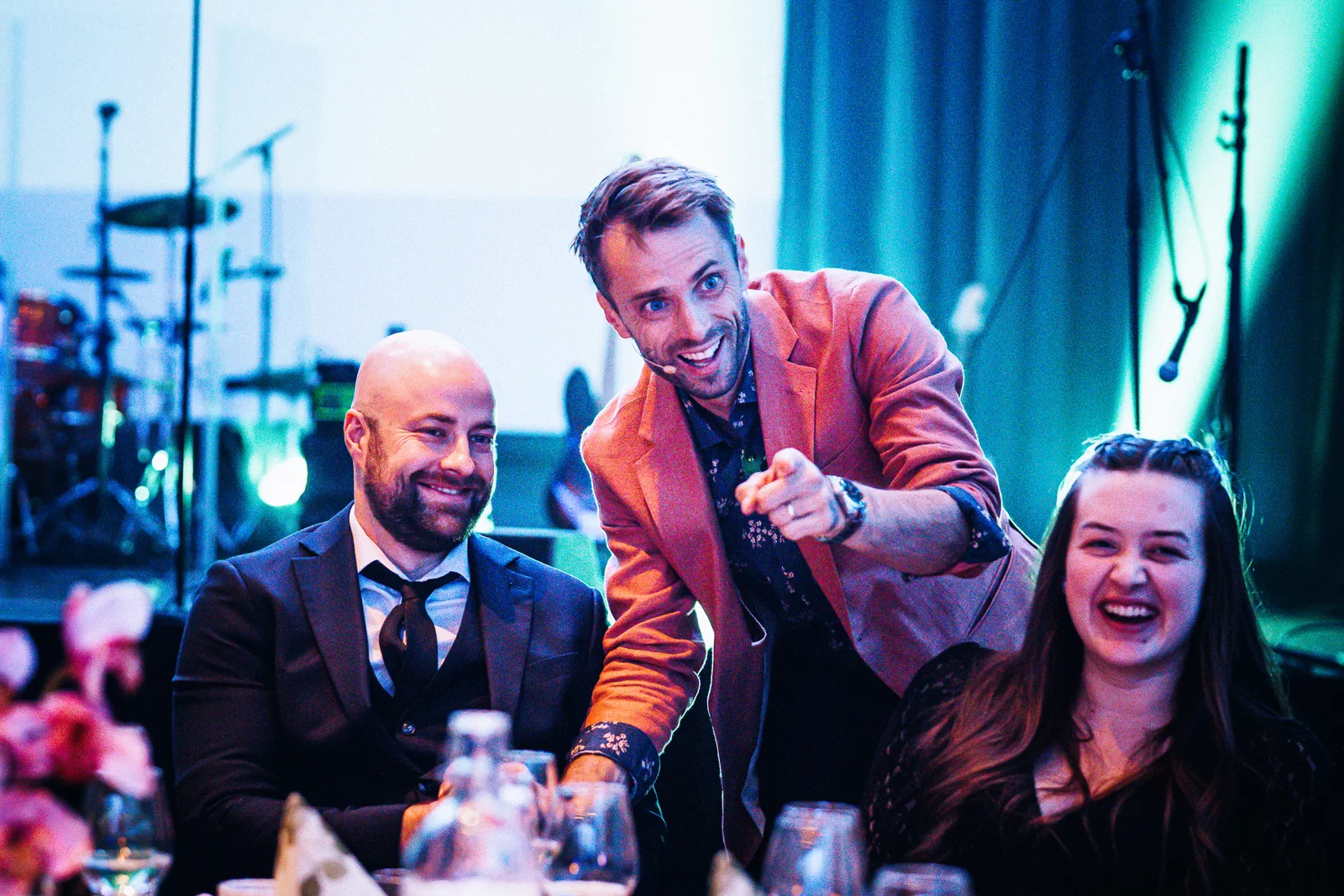 Hans Grane pointing and grinning between two laughing guests at a gala table