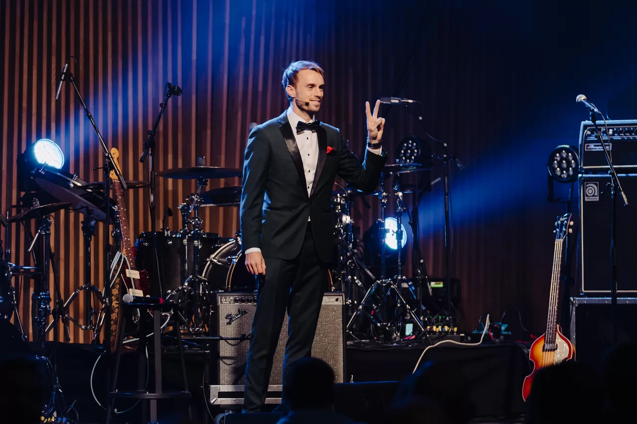 Hans Grane in black tie hosting a corporate gala on stage