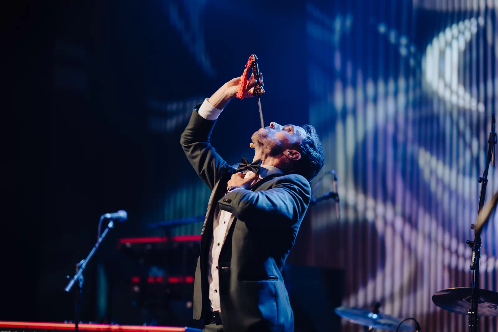 Hans Grane in black tie performing his corporate stage show under spotlights